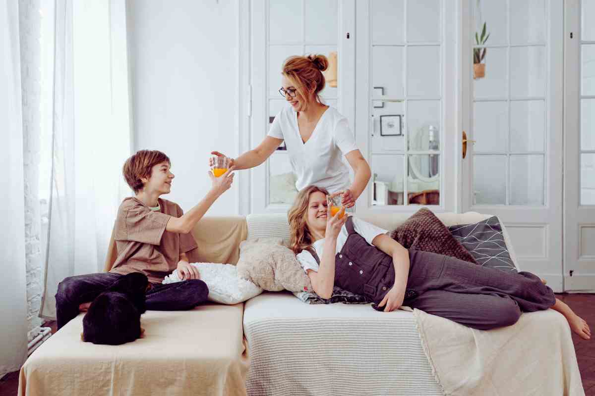 ragazzi su un divano e donna che porge un bicchiere